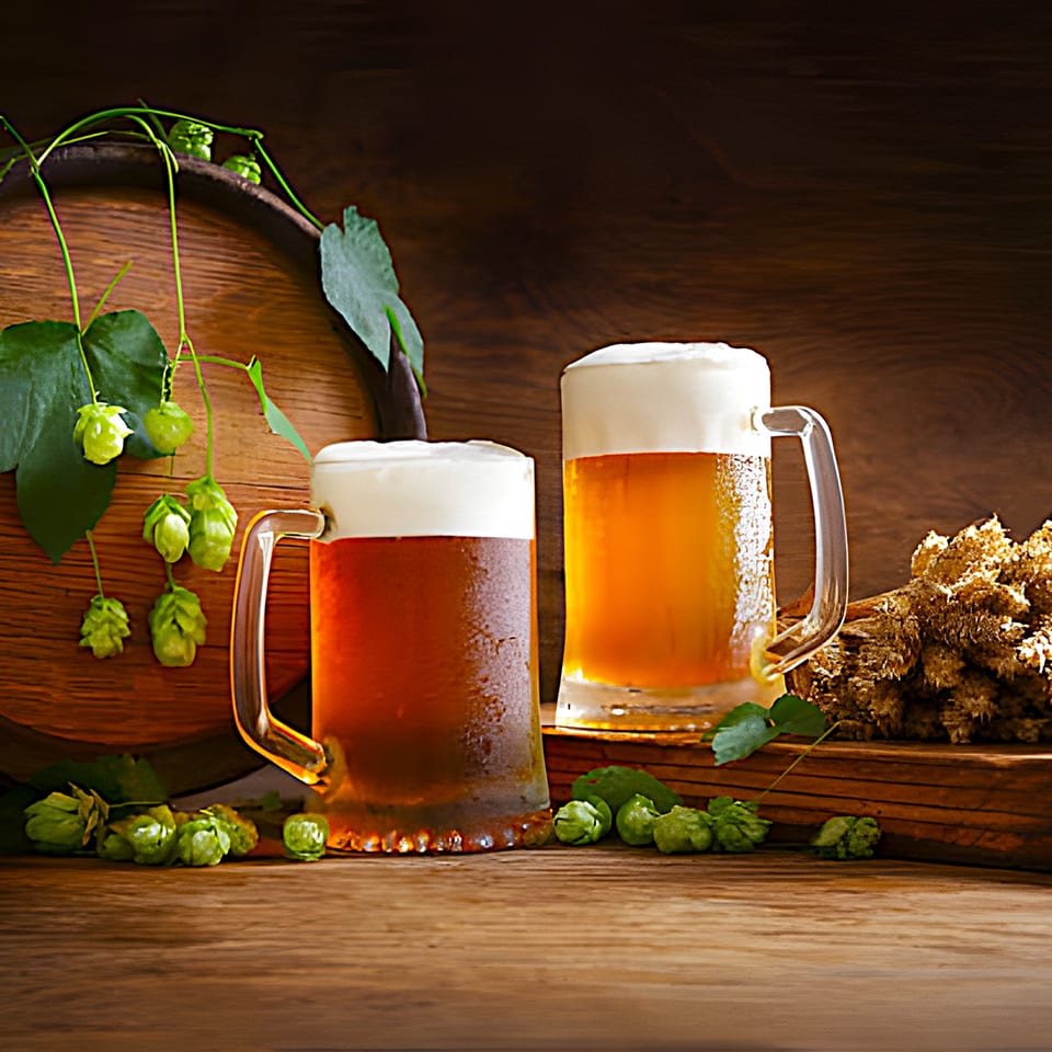 Two frosty mugs of beer with hops and a wooden barrel on a rustic wooden table.