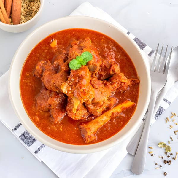 A bowl of Charminar Indian Grill & Bar's mutton curry, garnished with mint, on a white napkin.
